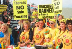 A group of protestors calling for a fracking ban, dressed in yellow t-shirts and holding placards.