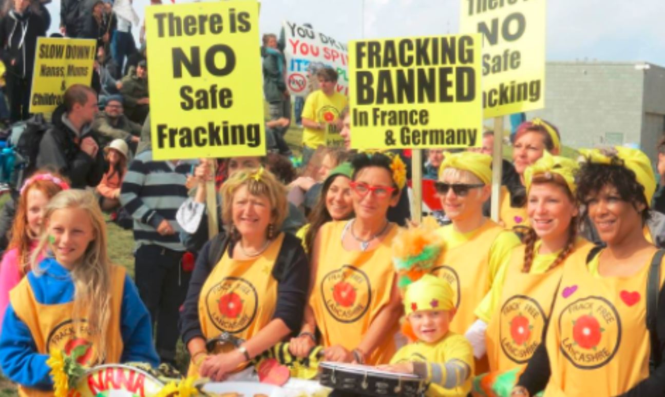 A group of protestors calling for a fracking ban, dressed in yellow t-shirts and holding placards.