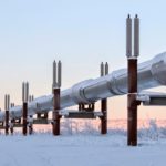 An energy supply pipe stretches across a snowscape, tinted by a pink sun, illustrating the impact of the conflict on gas and oil prices.